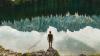 man standing on rock in front of lake