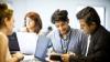 4 people looking at a report and laptops