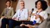 Woman holding a microphone sat next to two men who are looking at her.