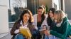 Four women sat looking at a book together with coffee