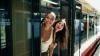 Two women, smiling, as they lean out of a train that is standing at a train station.