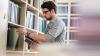 Man in a library taking a book from a shelf