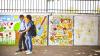 Two men walking in front of a colourful wall in India