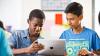 Two young students work together on a tablet