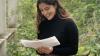 Young woman sitting in garden reading her notes.