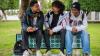 Three young men sit together on a bench chatting