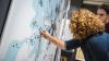 A woman writing on a map drawn on a wall