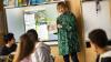 A young teacher teaching pupils in a classroom, showing them a book