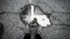 plane image reflected in a street puddle with feet visible