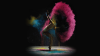 A woman dancing in a cloud of coloured powder on a dark background