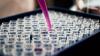 pipette with pink liquid over many test tubes