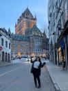 Woman standing in front of large building on street in Quebec. 