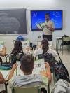Man standing in front of a class, teaching students who are holding a textbook. 